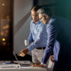Two men who have a laptop in front of them: One man shows the other something on the screen in onOffice enterprise.